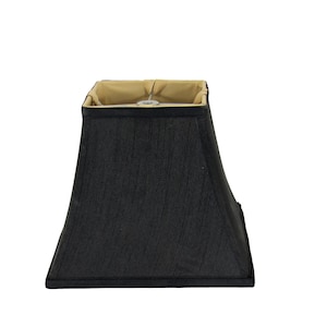 Könnte beinhalten: Ein schwarzer, quadratischer Lampenschirm mit leicht ausgestellter Form. Der Innenraum ist hellbeige und der Schirm hat eine strukturierte Optik. Der Lampenschirm ist für die Montage auf einem Lampensockel konzipiert.