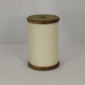 May include: A wooden spool with white thread wound around it. The spool has a brown wooden top and bottom.