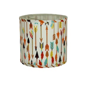 May include: A white drum lampshade with a pattern of colorful arrows and feathers.