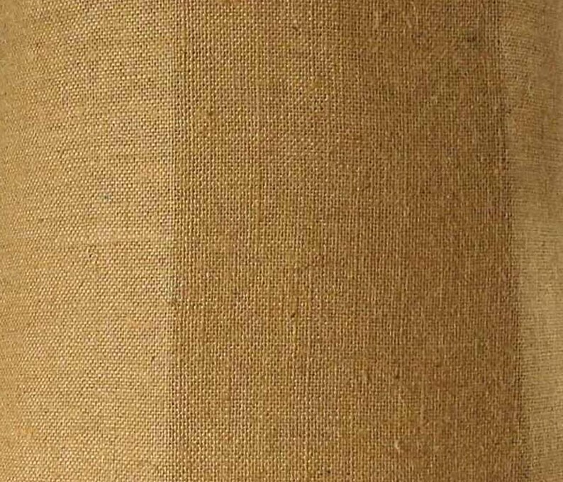 May include: A close-up of a brown burlap fabric with a slightly lighter brown vertical stripe running down the center.