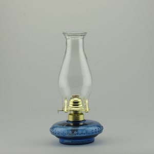 May include: A blue glass oil lamp with a clear glass chimney and a brass burner.