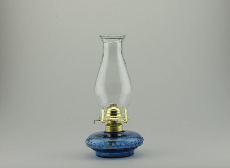 May include: A blue glass oil lamp with a clear glass chimney and a brass burner.