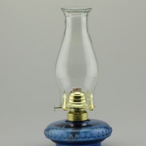 May include: A blue glass oil lamp with a clear glass chimney and a brass burner.