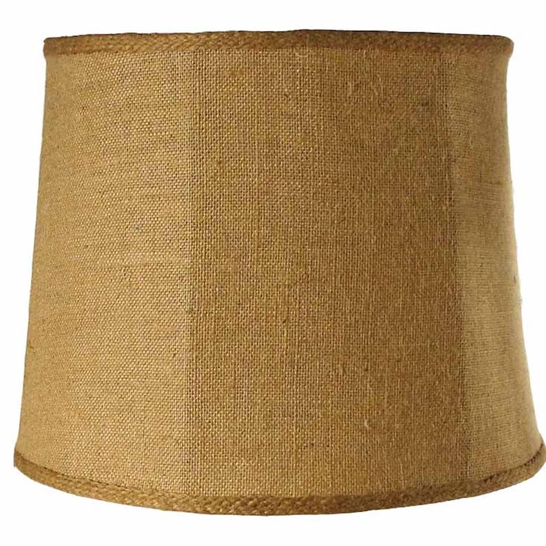 May include: A brown, round lampshade made of burlap with a woven texture. The lampshade has a simple design and a natural, rustic look.