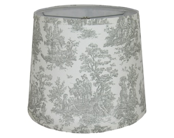 May include: A white lampshade with a gray toile pattern featuring a pastoral scene with trees, people, and animals.