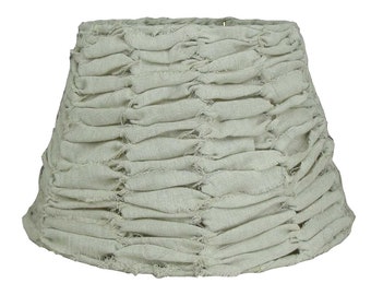 May include: A beige lampshade with a ruffled fabric design. The fabric has a slightly distressed look, giving it a rustic feel.