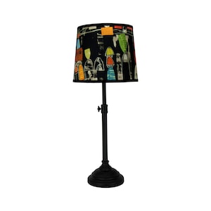 May include: A black table lamp with a black metal base and a colourful abstract patterned lampshade.