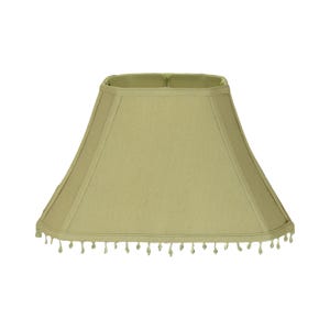 May include: A light green, trapezoid-shaped lampshade with a square top. The lampshade has a fabric texture and is trimmed with small, dangling beads along the bottom edge. The lampshade is designed to fit over a lamp base.