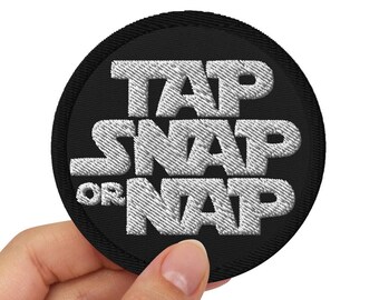 May include: A black round patch with white embroidered text that reads "Tap Snap Or Nap".