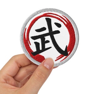 May include: A white round patch with a red circle and black kanji characters that say "道" in the center. The patch has a gray border.