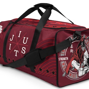 Puede incluir: Bolsa de deporte roja y negra con un diseño de Jiu-Jitsu. La bolsa presenta un gráfico de dos figuras en un combate de grappling, con el texto "TRUST, STRENGTH, INTEGRITY, WORLDWIDE" alrededor del gráfico. La bolsa también presenta el texto "JIU JITS" y un patrón de estrellas.