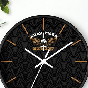 May include: Black and gold wall clock with a Krav Maga logo and the text "Krav Maga" and "להגנה עצמית". The clock has a black background with a wave pattern.