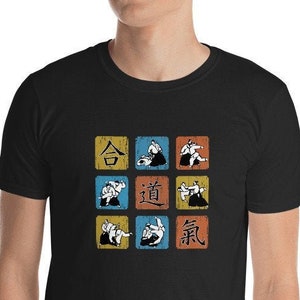 Könnte beinhalten: Schwarzes T-Shirt mit einem Design im Vintage-Stil, das neun Quadrate mit verschiedenen Judo-Würfen und die japanischen Schriftzeichen für "Judo" in der Mitte zeigt.