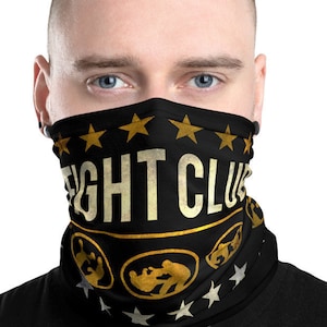 Może przedstawiać: Czarna maska ​​na twarz z wzorem w kolorze złotym i białym. Maska ​​zawiera napis "FIGHT CLUB" z gwiazdami i grafiką dwóch walczących postaci.