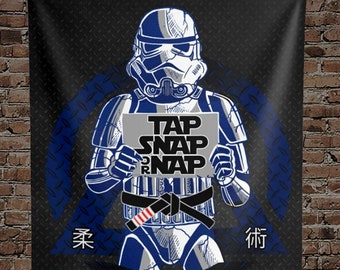 May include: A black and blue Jiu-Jitsu themed wall tapestry featuring a Star Wars Stormtrooper holding a sign that says "Tap Snap R-Nap".