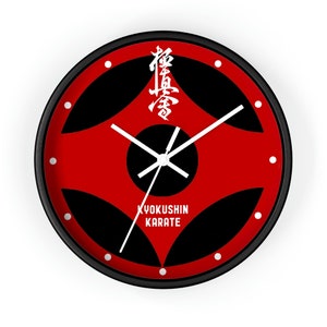 Może przedstawiać: Czarny i czerwony zegar ścienny z białymi wskazówkami i białym napisem "Kyokushin Karate". Tarcza zegara ma czarny i czerwony wzór z białym japońskim znakiem w środku.