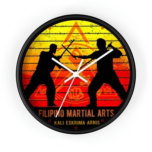 May include: A black and white clock with a yellow, orange, and red background. The clock face features two figures in silhouette, holding sticks, with the text "Filipino Martial Arts Kali Eskrima Arnis".