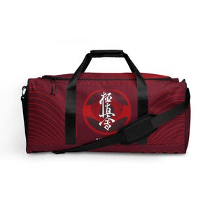 Könnte beinhalten: Rote und schwarze Reisetasche mit einem weißen Kanji-Symbol und dem Wort "Kyu" auf der Vorderseite.