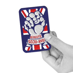 May include: A blue and red embroidered patch with a white fist and the text "KARATE GOJU-RYU" in red.