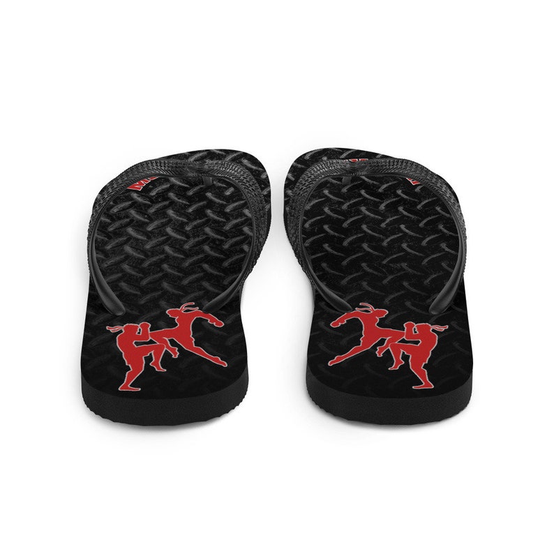 May include: Pair of black flip flops with a diamond plate pattern. The flip flops have a red silhouette of two people in a fighting stance.