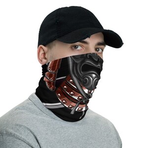 Pode incluir: Uma m&aacute;scara facial preta com um gr&aacute;fico de um capacete e uma m&aacute;scara de um guerreiro samurai. O design apresenta um esquema de cores vermelho e marrom.