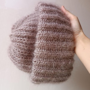 May include: A soft, fluffy, pink knitted hat with a ribbed texture.