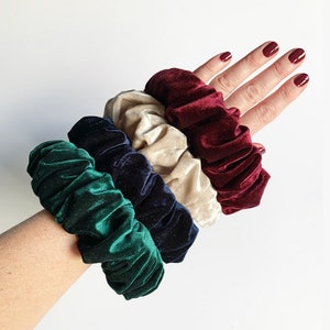 May include: Four velvet scrunchies in different colors: green, navy blue, cream, and burgundy.