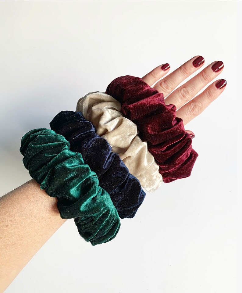 May include: Four velvet scrunchies in different colors: green, navy blue, cream, and burgundy.