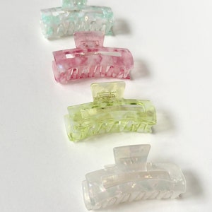 Puede incluir: Cuatro pinzas para el pelo en diferentes colores: azul claro, rosa, verde claro y blanco. Las pinzas son de plástico y tienen un patrón de mármol.