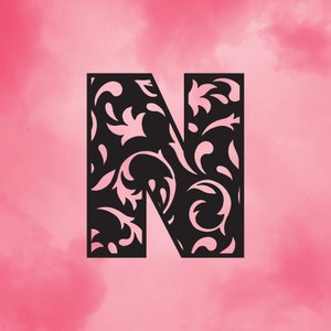 May include: A black letter "N" with a floral design against a pink background. The floral design is intricate and detailed, with swirling patterns and leaf-like shapes. The background has a soft, watercolor-like effect.