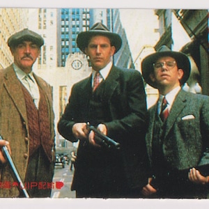 Puede incluir: Una imagen promocional de la película "Los Intocables" con cuatro hombres con trajes y sombreros, de pie en una calle de la ciudad. La imagen tiene texto japonés y el título de la película en inglés. Una sección roja a la izquierda tiene texto japonés.