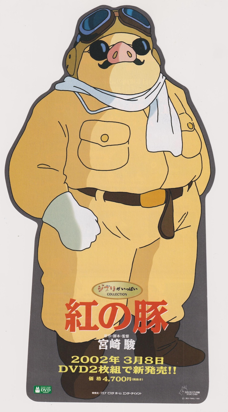 Peut inclure: Une d&eacute;coupe promotionnelle d'un personnage cochon portant une combinaison de vol beige, une &eacute;charpe blanche et des lunettes d'aviateur. Le texte inclut "紅の豚", "宮崎駿" et "2002年3月8日 DVD2枚組で新発売!!". Le personnage a une moustache noire et porte des lunettes de soleil.