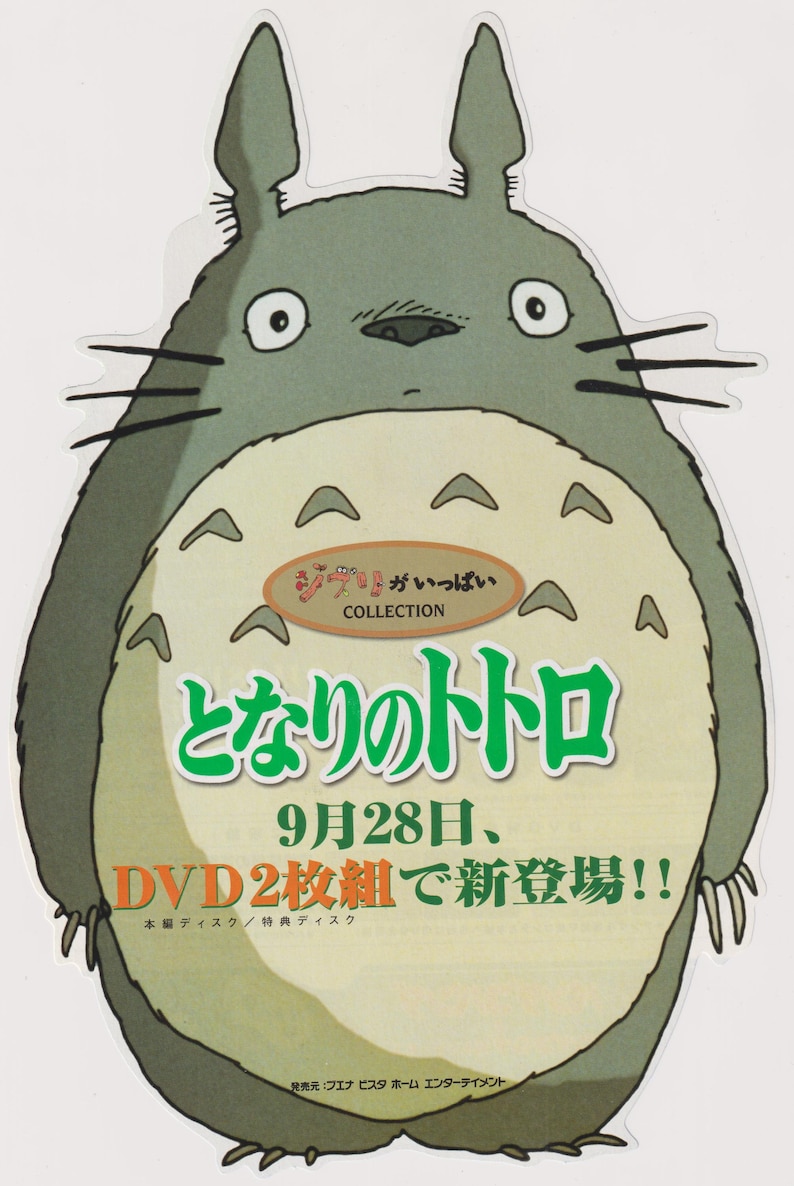 May include: A die-cut sticker featuring the character Totoro, a large grey creature with a beige belly and pointed ears. The image includes Japanese text, the word COLLECTION, and the phrase 9月28日、DVD2枚組で新登場!! printed in black, green, and orange.