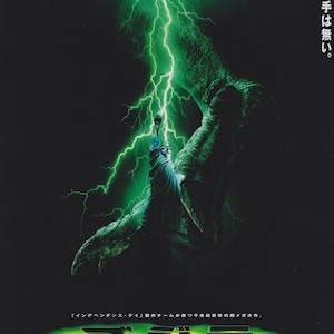 Può includere: Un poster del film "Godzilla" che mostra un mostro verde che distrugge la Statua della Liberté. Il poster ha uno schema di colori verde e giallo e il testo "Godzilla" è scritto in grandi caratteri grassetto.
