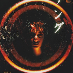 Peut inclure: Affiche de film pour le film d'horreur japonais "The Ring" mettant en scène le visage d'une femme dans un anneau rouge et orange. Le texte sur l'affiche est "The Ring" en anglais et "リング" en japonais.