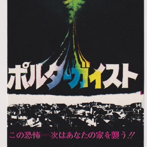 May include: Movie poster for the film "Poltergeist" featuring a child peeking over a pink blanket, with colorful streaks emanating from a central point. Japanese text is prominent, along with English text.