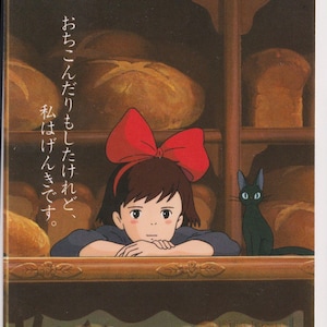 May include: A promotional poster for the animated film "Kiki's Delivery Service." The image features a young girl with a large red bow, a black cat, and various baked goods. Japanese text is visible.