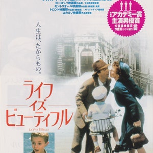 May include: A movie poster for the film "Life is Beautiful" (La Vita è Bella) featuring a man and woman kissing in the background, a young boy on a bicycle in the foreground, and the film's title in large red letters. The poster also includes the text "'98 Cannes Film Festival Jury Prize Winner" and "Academy Award Nominee for 7 Awards".
