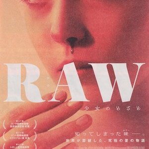 May include: A movie poster for the film "RAW" in Japanese. The poster features a close-up of a woman's face with blood dripping from her nose. The title of the film is written in large white letters across the bottom of the poster. The text "少女のめざめ" is written in smaller white letters below the title. The text "知ってしまった味" is written in smaller white letters below the text "少女のめざめ". The text "世界が震撼した、究極の愛の物語" is written in even smaller white letters below the text "知ってしまった味".