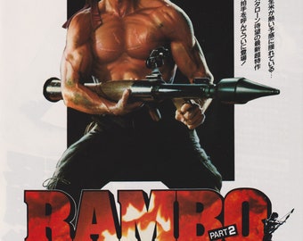 May include: A movie poster for the action film "Rambo: Part 2" featuring Sylvester Stallone as John Rambo. The poster has a red and white color scheme with the title "Rambo" in large, bold letters. The poster also includes the text "Super Series 2nd Episode/Anger's Escape" and "Sylvester Stallone".