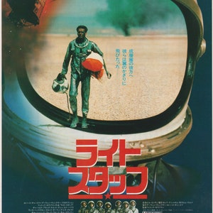 Puede incluir: Un póster de película para la película "The Right Stuff" con una estrella roja y el texto "ライト スタッフ" en japonés. El póster presenta un primer plano de un casco de astronauta con una vista de un hombre con un traje espacial caminando a través de un paisaje desértico. El texto "人類には“夢”男たちには“挑戦”" también es visible en el póster.