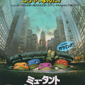May include: A movie poster for the 1990 film "Teenage Mutant Ninja Turtles". The poster features four green turtles with bandanas, emerging from a sewer grate in front of a cityscape. The poster is in Japanese and includes the text "Mutant Turtles" and "Cowabunga!"