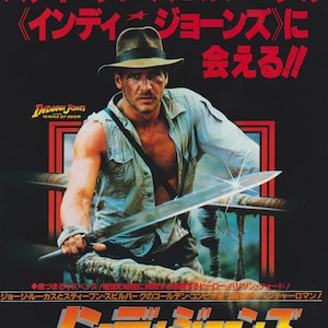 May include: A movie poster for the 1984 film Indiana Jones and the Temple of Doom. The poster features a photo of Harrison Ford as Indiana Jones holding a machete. The text on the poster reads "84 Summer Steven Spielberg's Indiana Jones Temple of Doom".