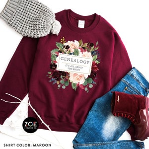 May include: Maroon sweatshirt with a floral design and the text "GENEALOGY IT'S ALL ABOUT THE ROOTS".