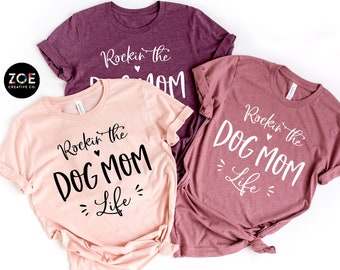 May include: Three t-shirts with the text "Rockin' the Dog Mom Life" in different colours: peach, heather mauve, and heather maroon.