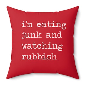 May include: Red throw pillow with white text that reads "i'm eating junk and watching rubbish".