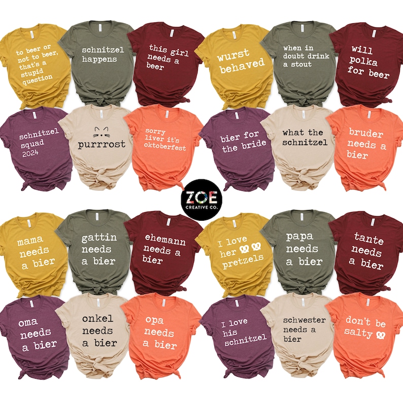 May include: A selection of t-shirts in various colours, each printed with a different humorous phrase. The shirts display slogans such as "Schnitzel Happens", "This Girl Needs a Beer", and "I Love Her Pretzels". The shirts are arranged in rows.