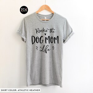 May include: Gray t-shirt with black text that reads "Rockin' the Dog Mom Life" with a small heart between "Rockin'" and "the".