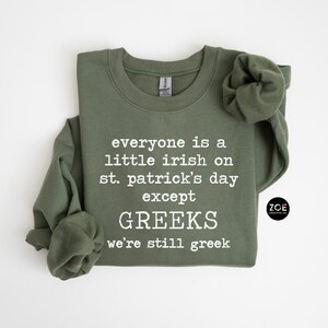 May include: A green sweatshirt with the text "everyone is a little irish on st. patrick's day except GREEKS we're still greek" printed in white. The sweatshirt has a crew neck and long sleeves.