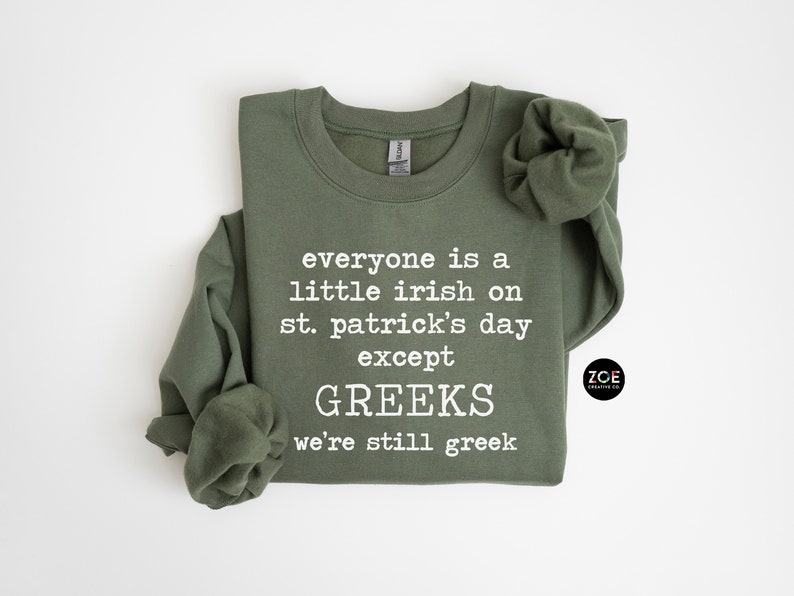 May include: A green sweatshirt with the text "everyone is a little irish on st. patrick's day except GREEKS we're still greek" printed in white. The sweatshirt has a crew neck and long sleeves.